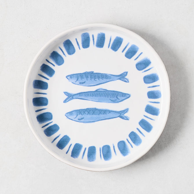 White terracotta salad plate with hand-painted blue sardines and a blue striped rim.