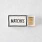 White ceramic matchbox with hand-drawn black border and the word MATCHES, filled with wooden matches.