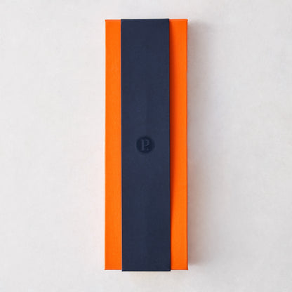 Perceval 9.47 knife set in a rectangular orange gift box with a navy blue branded sleeve on a white background.