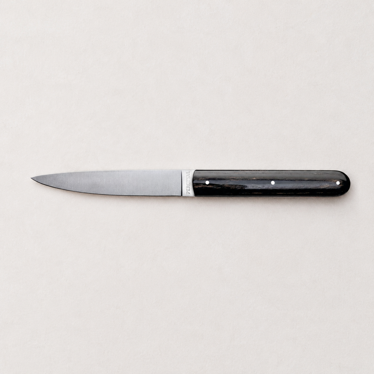 Perceval 9.47 stainless steel knife with a dark polished pakkawood handle on a neutral background.