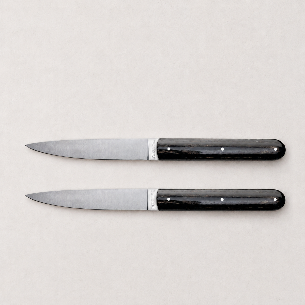 Set of two Perceval 9.47 steak knives with stainless steel blades and dark, polished pakkawood handles.