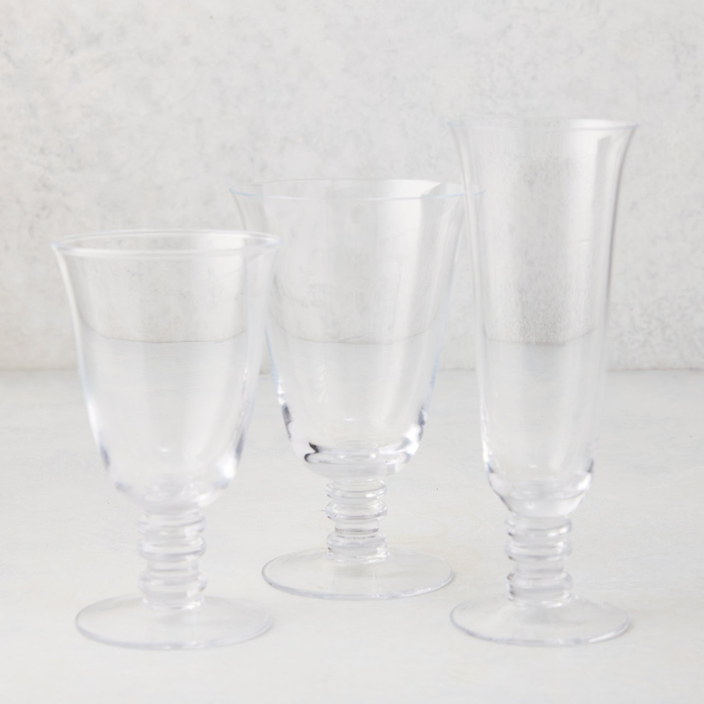 Three clear Palermo stemmed wine glasses of varying heights, hand-blown glass with artistic stems.