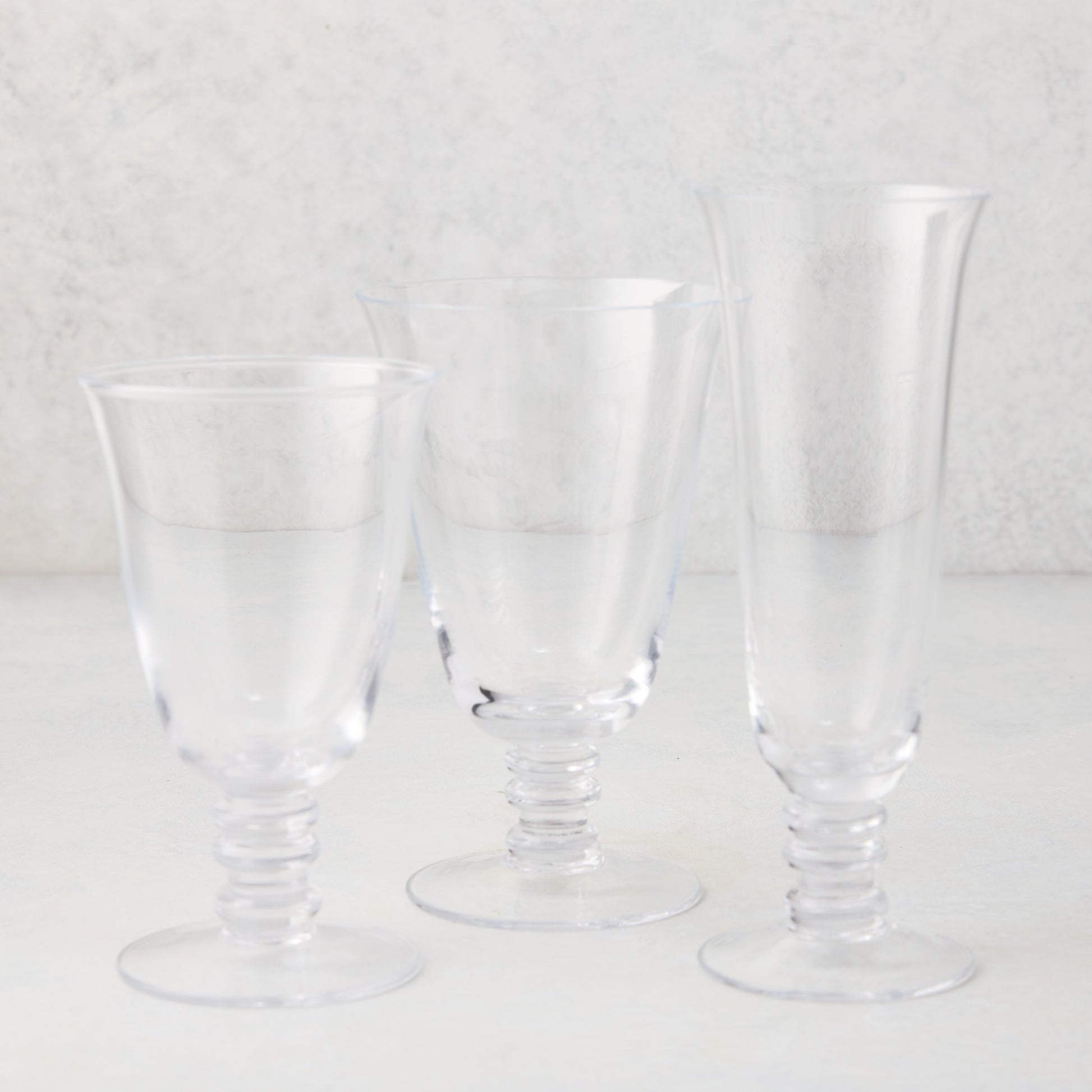 Three clear Palermo stemmed wine glasses of varying heights, hand-blown glass with artistic stems.