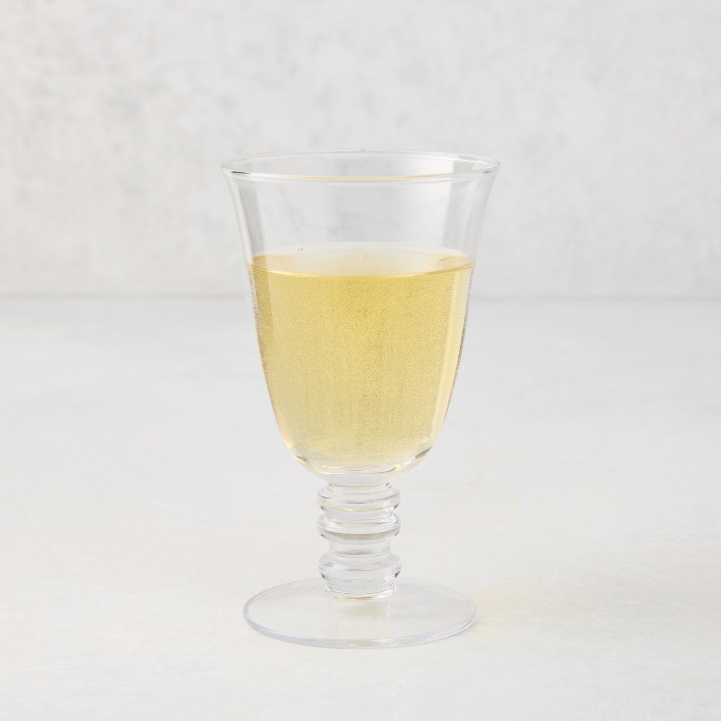 Palermo Stemmed Wine Glass, clear hand-blown glass with a curved lip and artistic ribbed stem, filled with white wine.