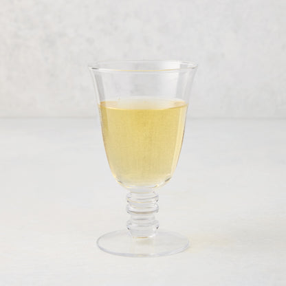 Palermo Stemmed Wine Glass, clear hand-blown glass with a curved lip and artistic ribbed stem, filled with white wine.