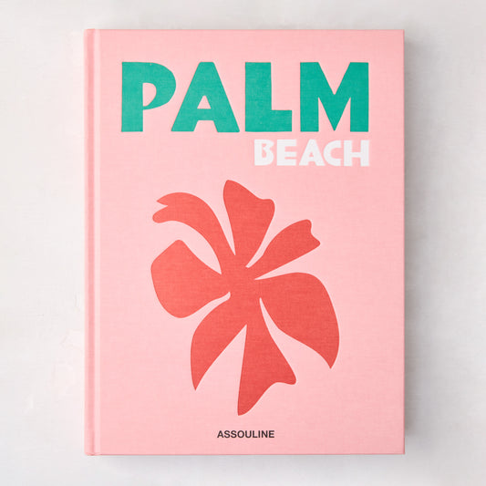 Pink hardcover "Palm Beach" book with green and white title, coral palm leaf graphic, and Assouline logo.