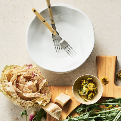 Paris Bistro 5-piece flatware set with stainless steel and cream acrylic handles resting in a white bowl on a table.
