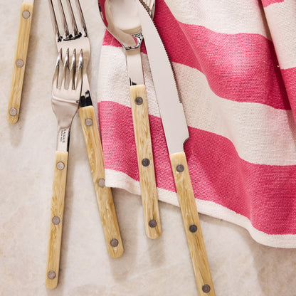 Paris Bistro 5-piece flatware set with stainless steel heads and cream-colored acrylic handles on a striped napkin.