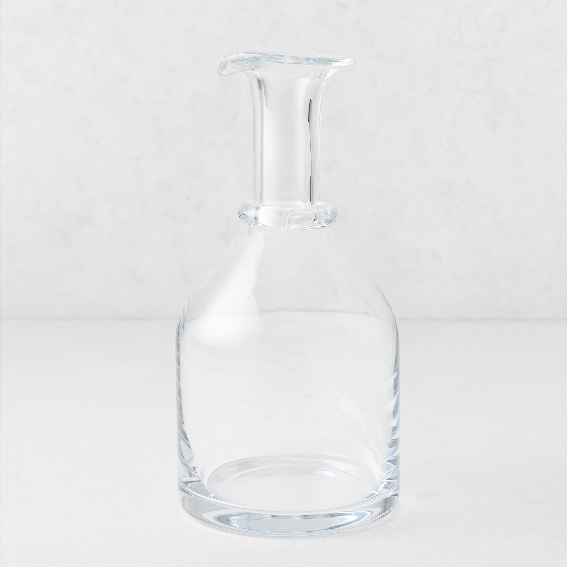 Clear mouth-blown crystalline glass wine carafe with a broad base, ridged neck, and rippled rim, 10 inches tall.