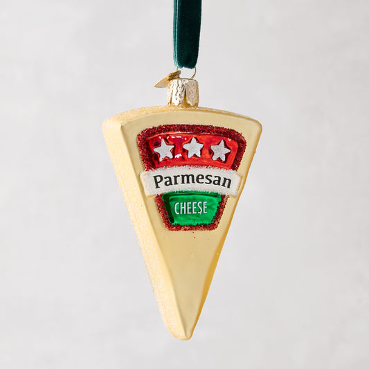 Hand-painted glass Parmesan cheese wedge Christmas ornament with glitter, red and green label, and velvet ribbon.