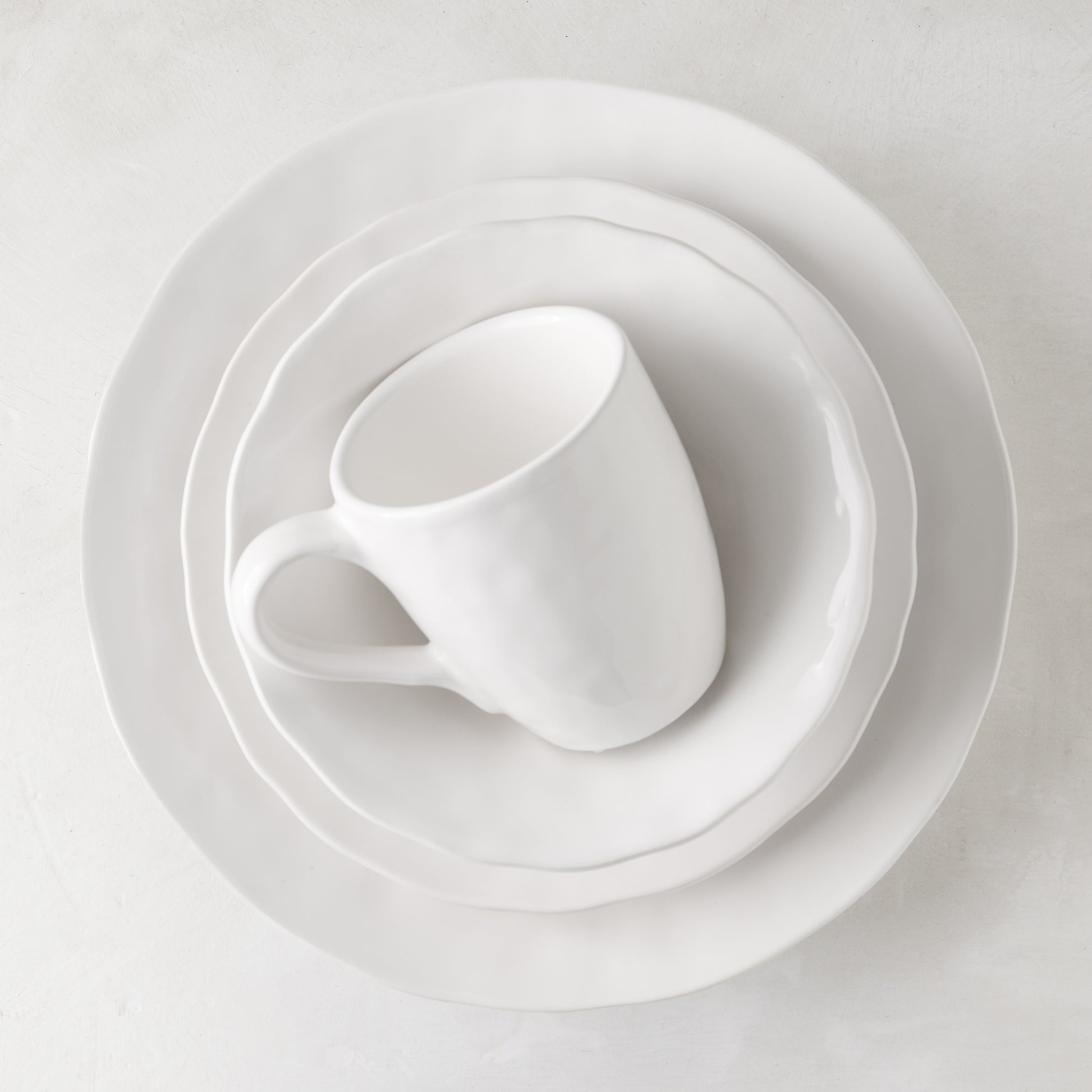 Pebble White ceramic mug and two plates, subtly textured, creamy white glaze.