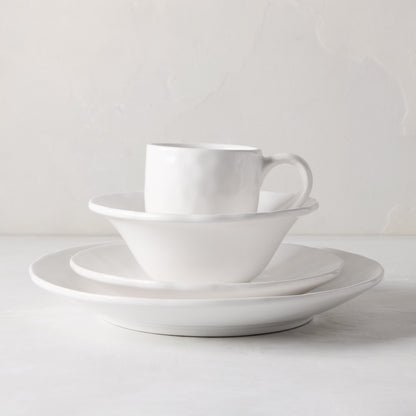 Stack of Pebble White ceramic dinnerware: mug, bowl, and two plates with subtle textures.
