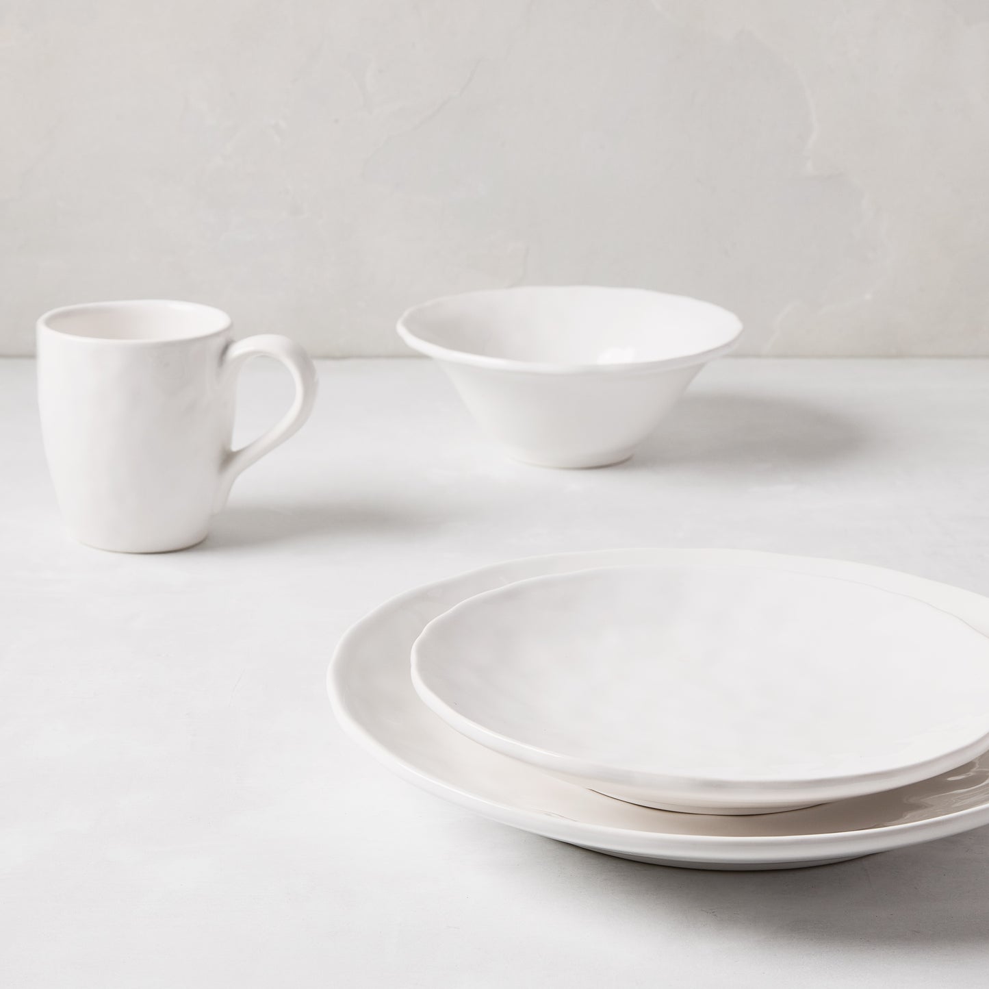 Pebble White ceramic mug, bowl, and two plates with subtle textures on a light background.