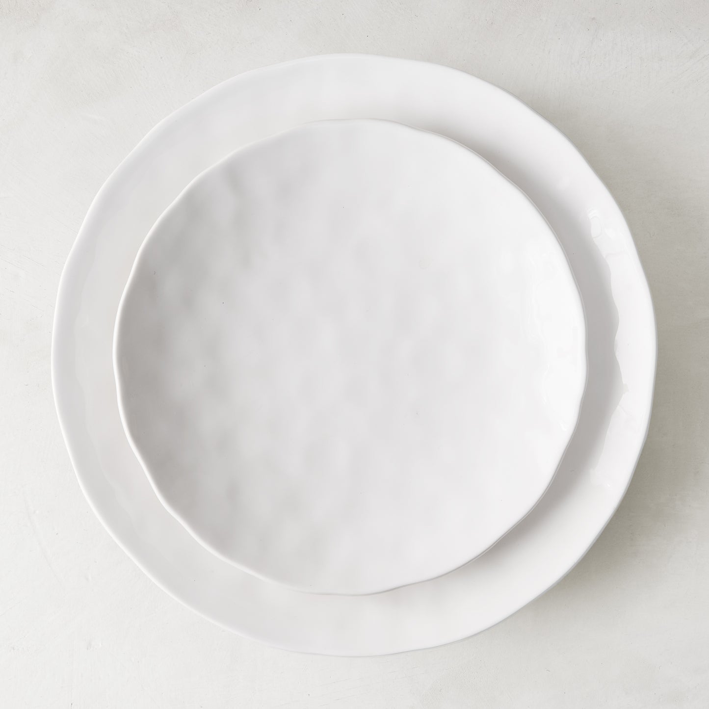 Pebble White 11" ceramic dinner plate with subtle textures, stacked on a larger white plate.