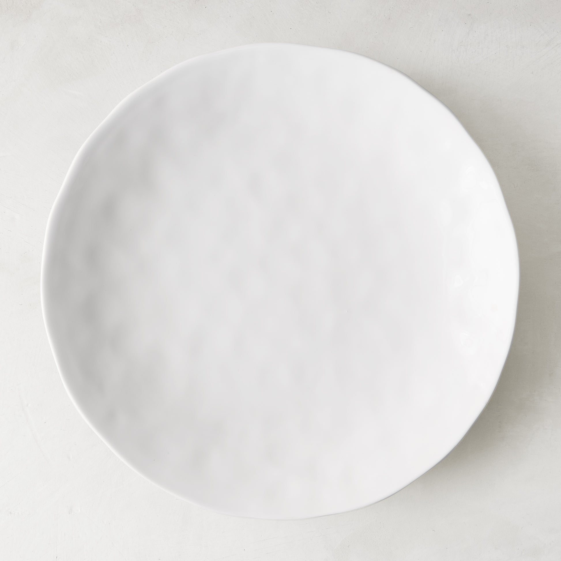 Pebble White 11" ceramic dinner plate with subtle textured surface and creamy white glaze.
