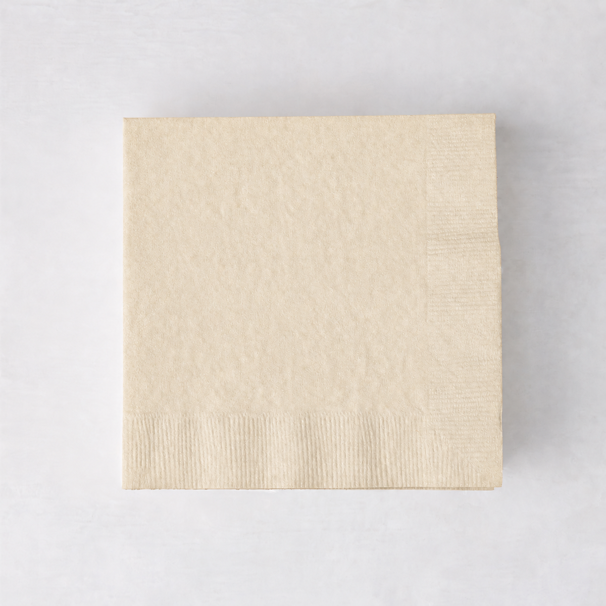 Square ivory 3-ply paper cocktail napkin with a textured border on a light background.