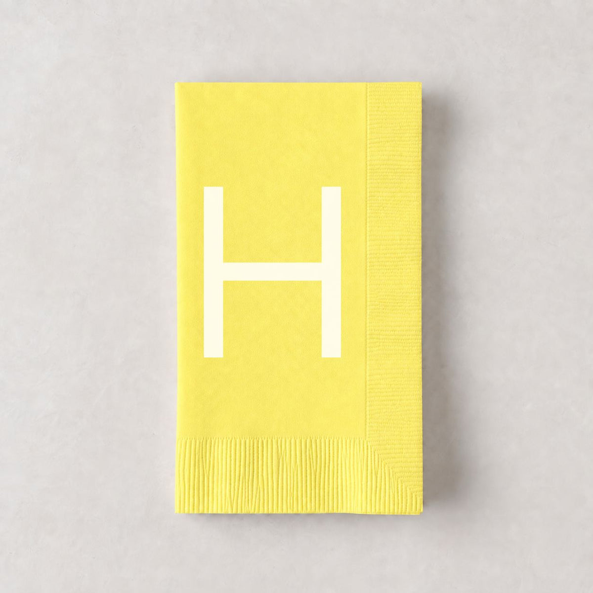 Pale yellow 3-ply paper hand towel with a white letter H monogram, 8 by 4.5 inches.