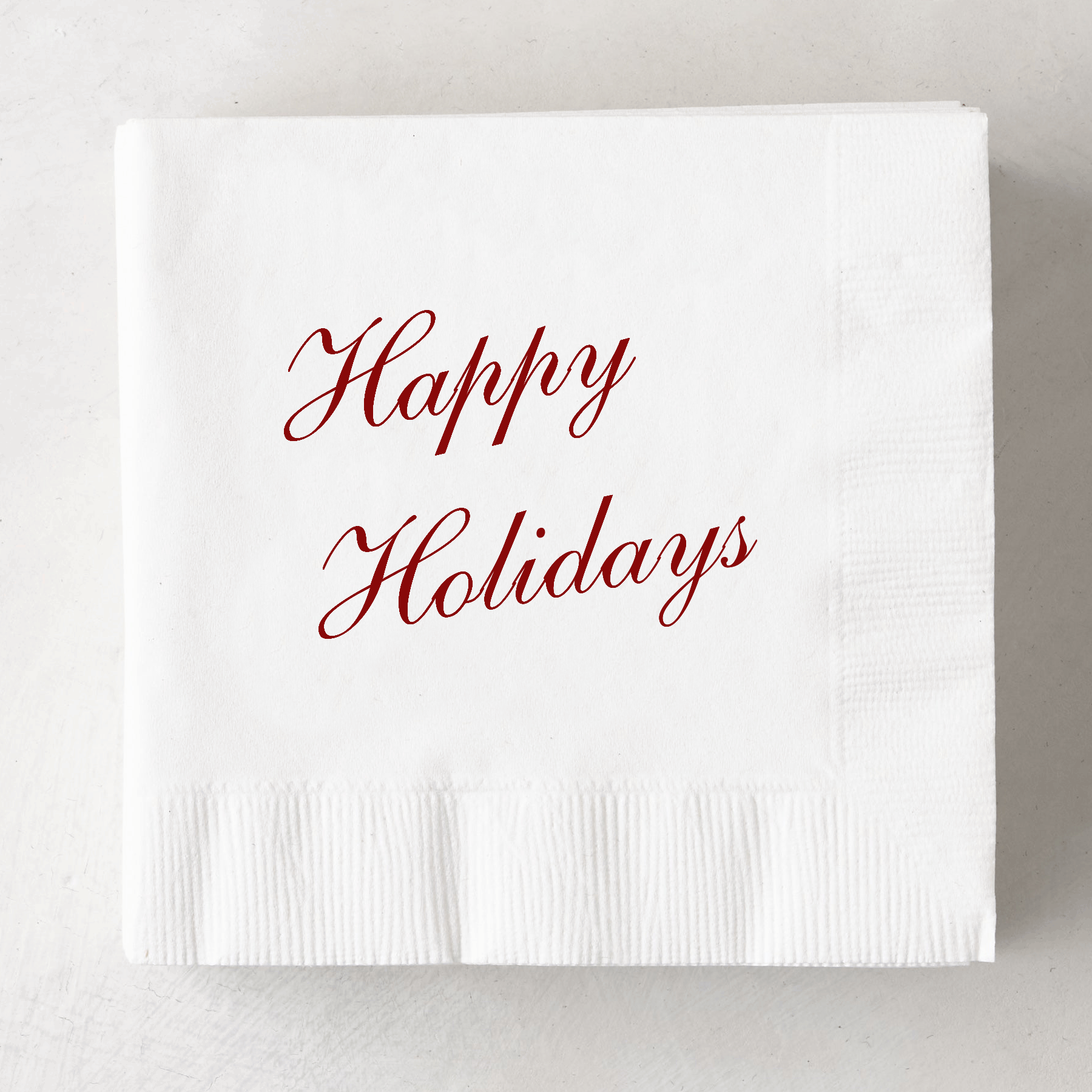 White 3-ply paper cocktail napkin with "Happy Holidays" in red script.