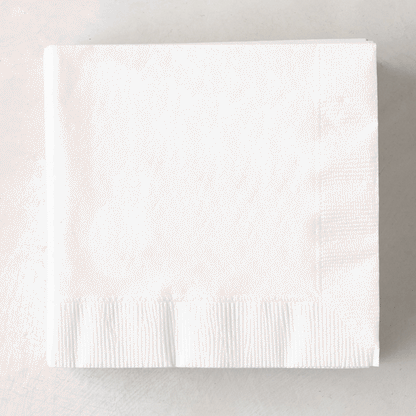 Stack of white 3-ply disposable paper cocktail napkins, 5.5" square.