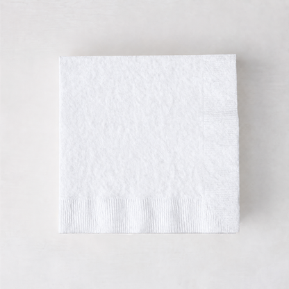 Square 5.5-inch white 3-ply paper cocktail napkin with a textured border on a light background.