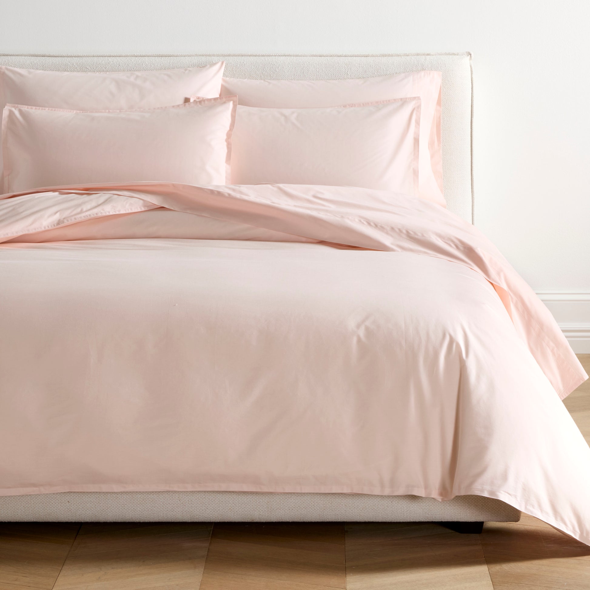 Petal Pink Italian Percale Duvet Set with two shams on a bed, showing soft, crisp cotton fabric.