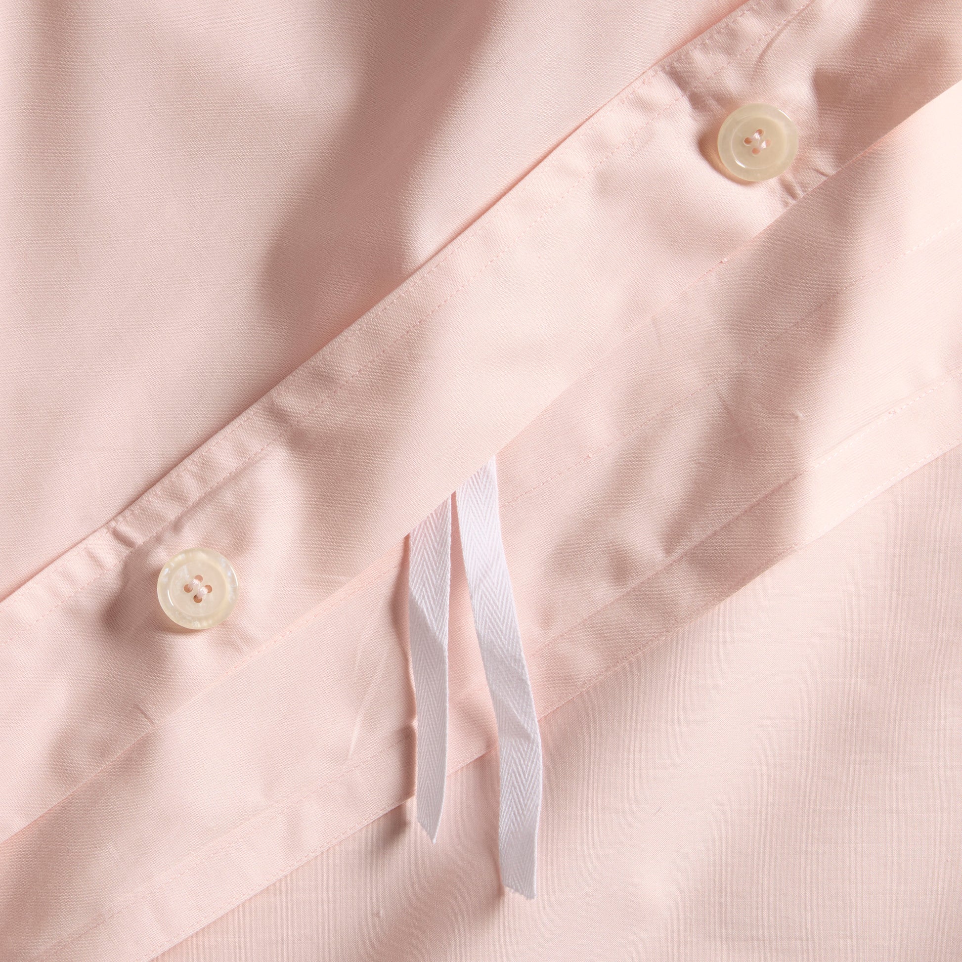 Close-up of Petal Pink Italian Percale Duvet Set with button closures and white ties.