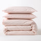 Stacked Petal Pink Italian Percale Duvet Set with two shams and a folded duvet cover.