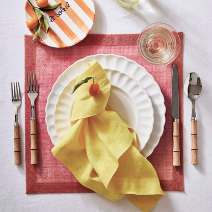 11.25-inch white glazed stoneware dinner plate with a scalloped petal edge, set on a red placemat with a yellow linen napkin.