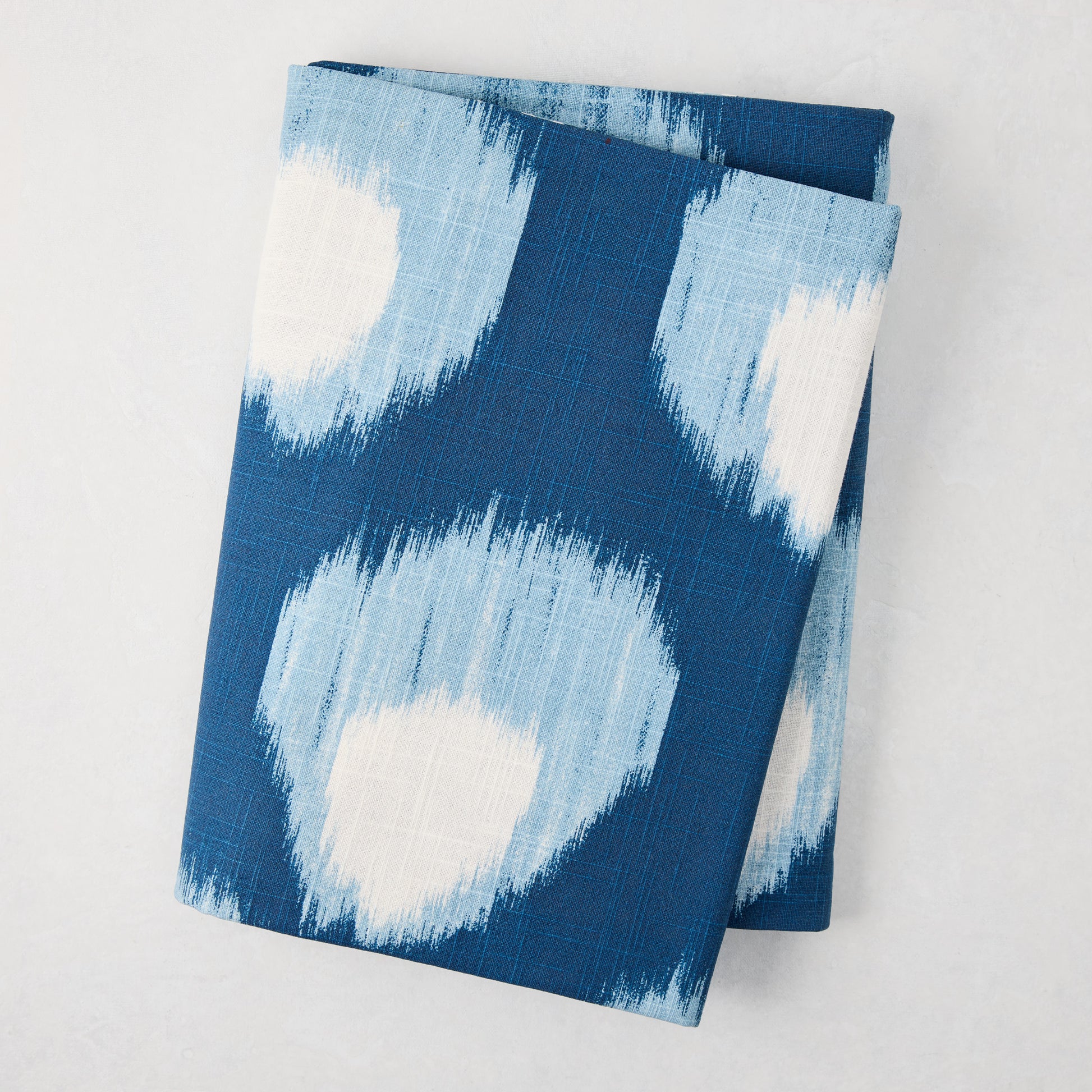 Folded Peter Dunham + Hudson Grace Blue Bukhara Ikat Printed Tablecloth, 100% cotton slub.