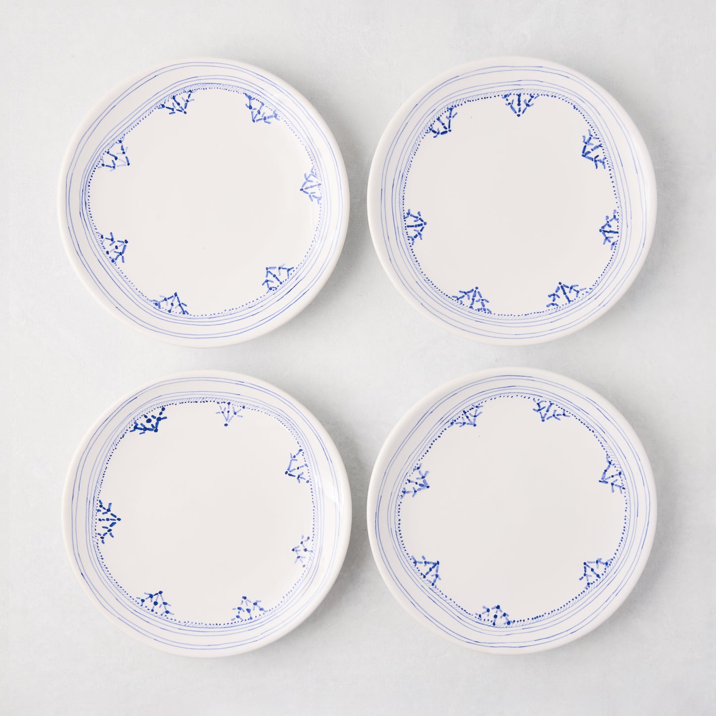 Four white Peter Dunham + Hudson Grace Blue Fez hand-painted border appetizer plates.