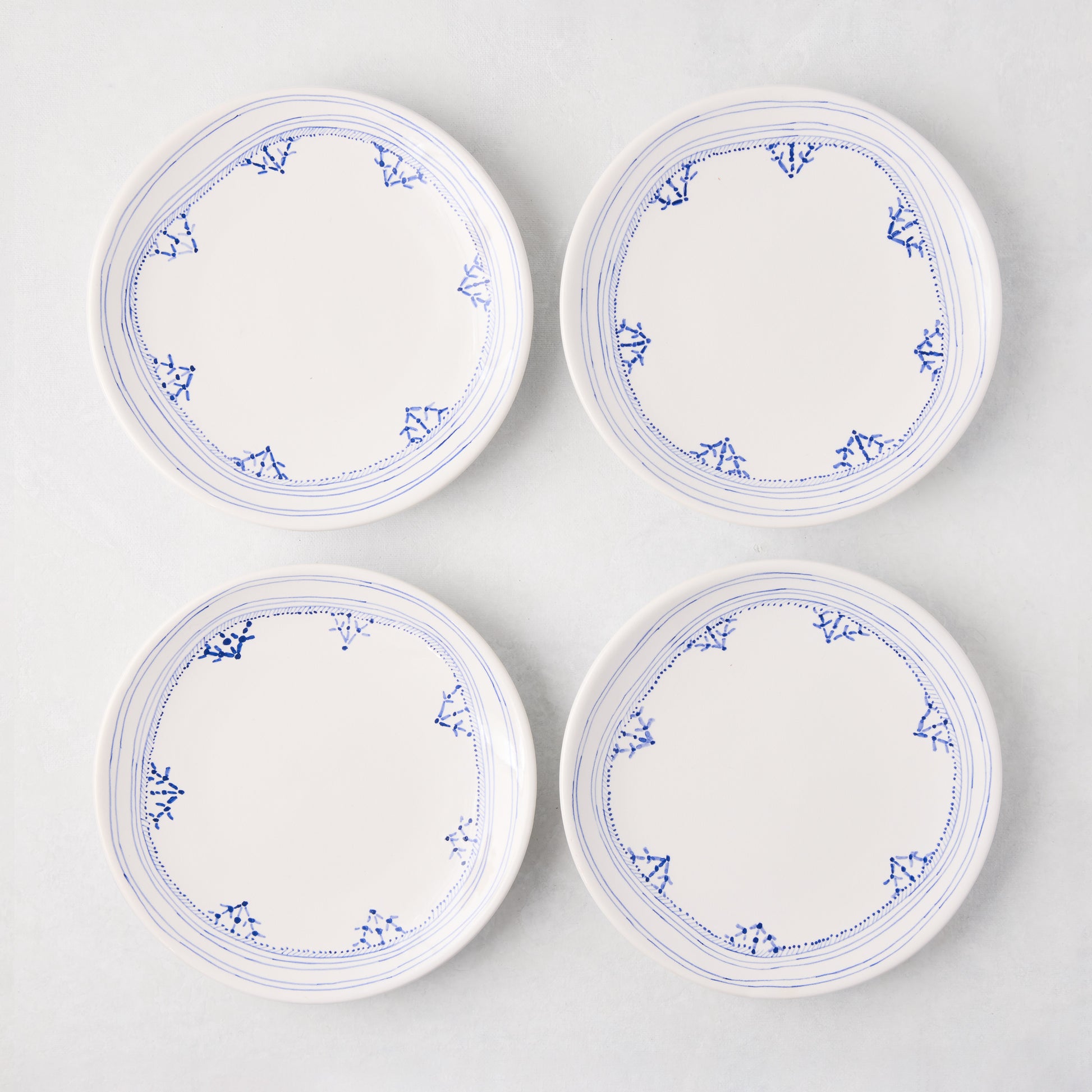 Four white Peter Dunham + Hudson Grace Blue Fez hand-painted border appetizer plates.