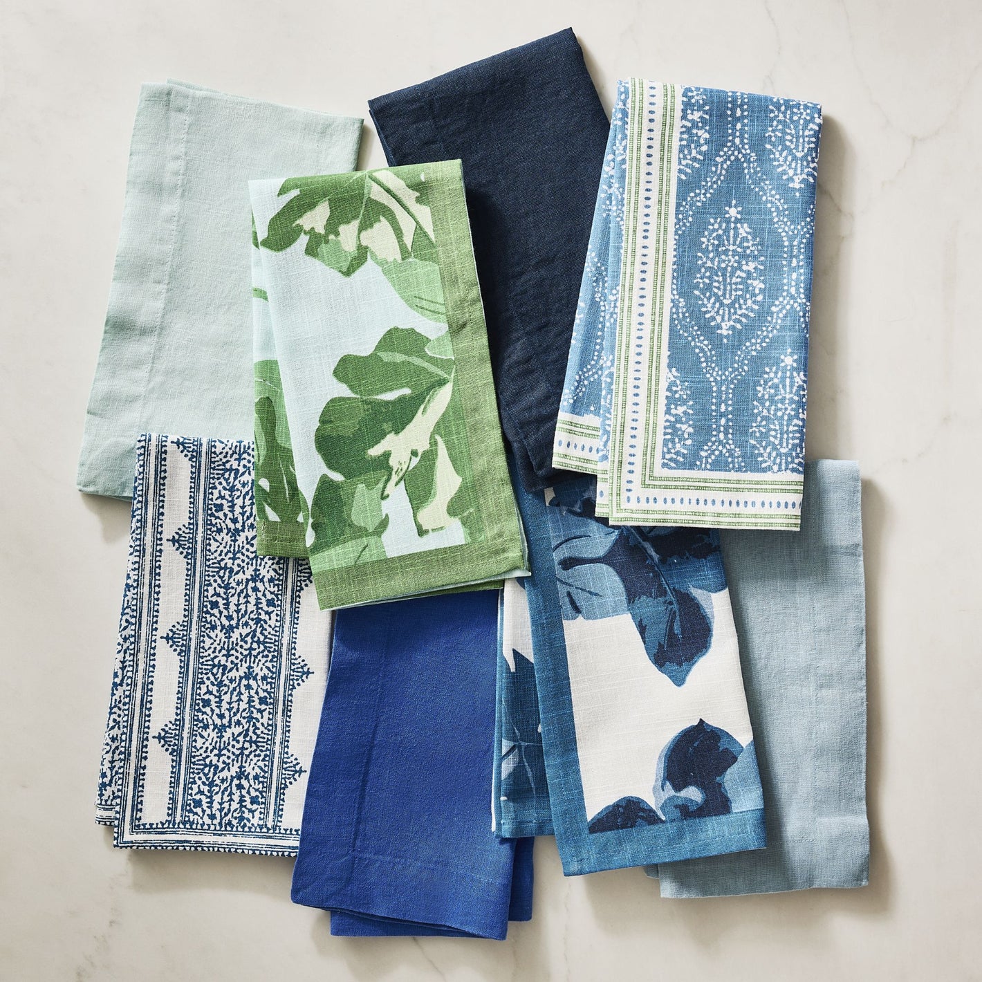 Assortment of Peter Dunham + Hudson Grace cotton napkins in blue, green, and white patterns and solids.