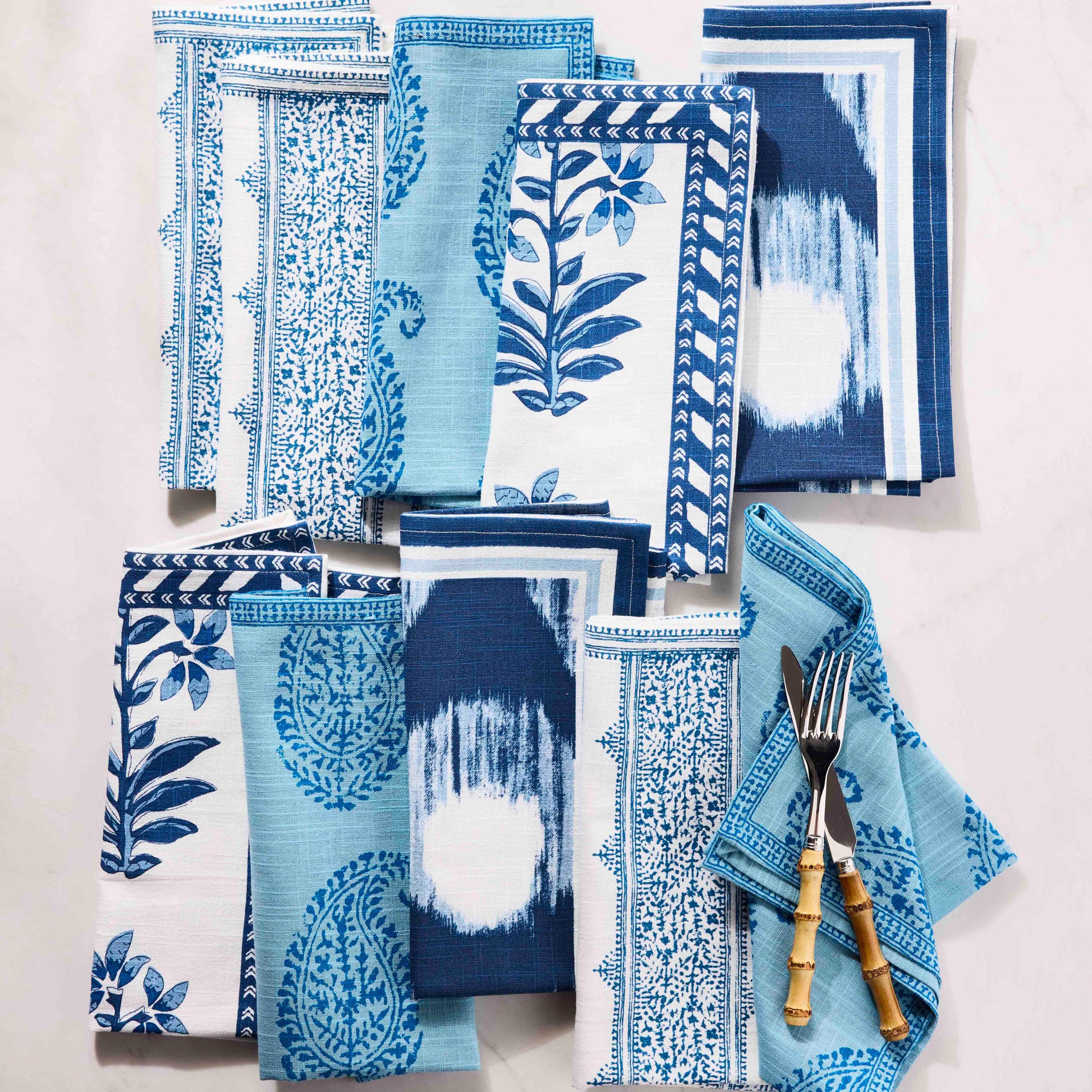 Peter Dunham + Hudson Grace Blue Fez Stripe cotton slub napkin with various blue patterned napkins and bamboo flatware.