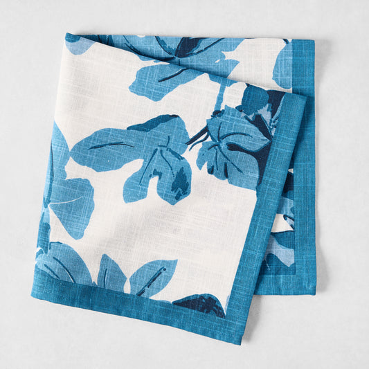 Peter Dunham + Hudson Grace Blue Fig Leaf printed white cotton slub napkin with blue border, folded.