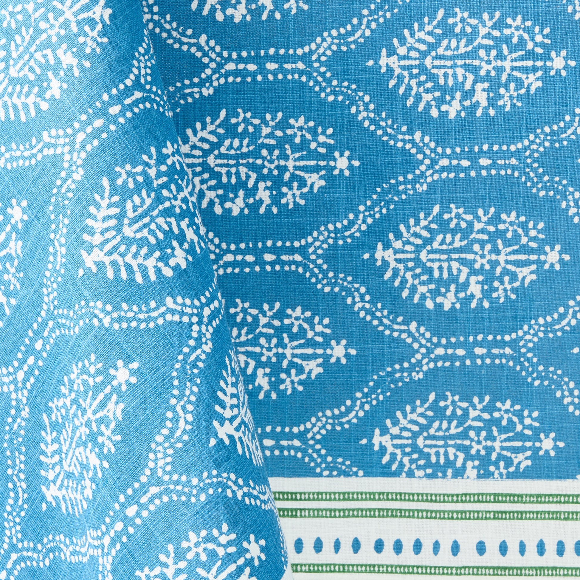 Blue Jaali printed cotton tablecloth with white floral pattern and green border detail.