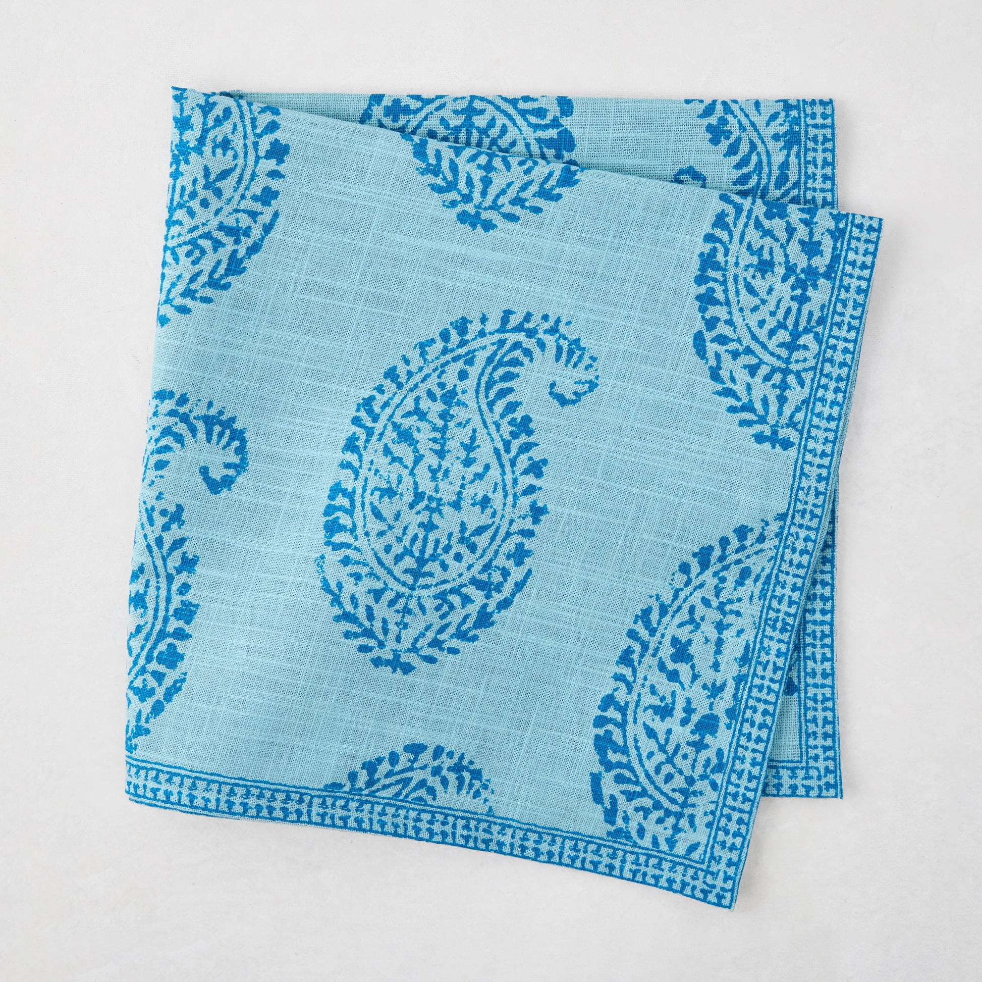 Folded Peter Dunham + Hudson Grace Blue Kashmir Paisley Printed Napkin with intricate blue block print.