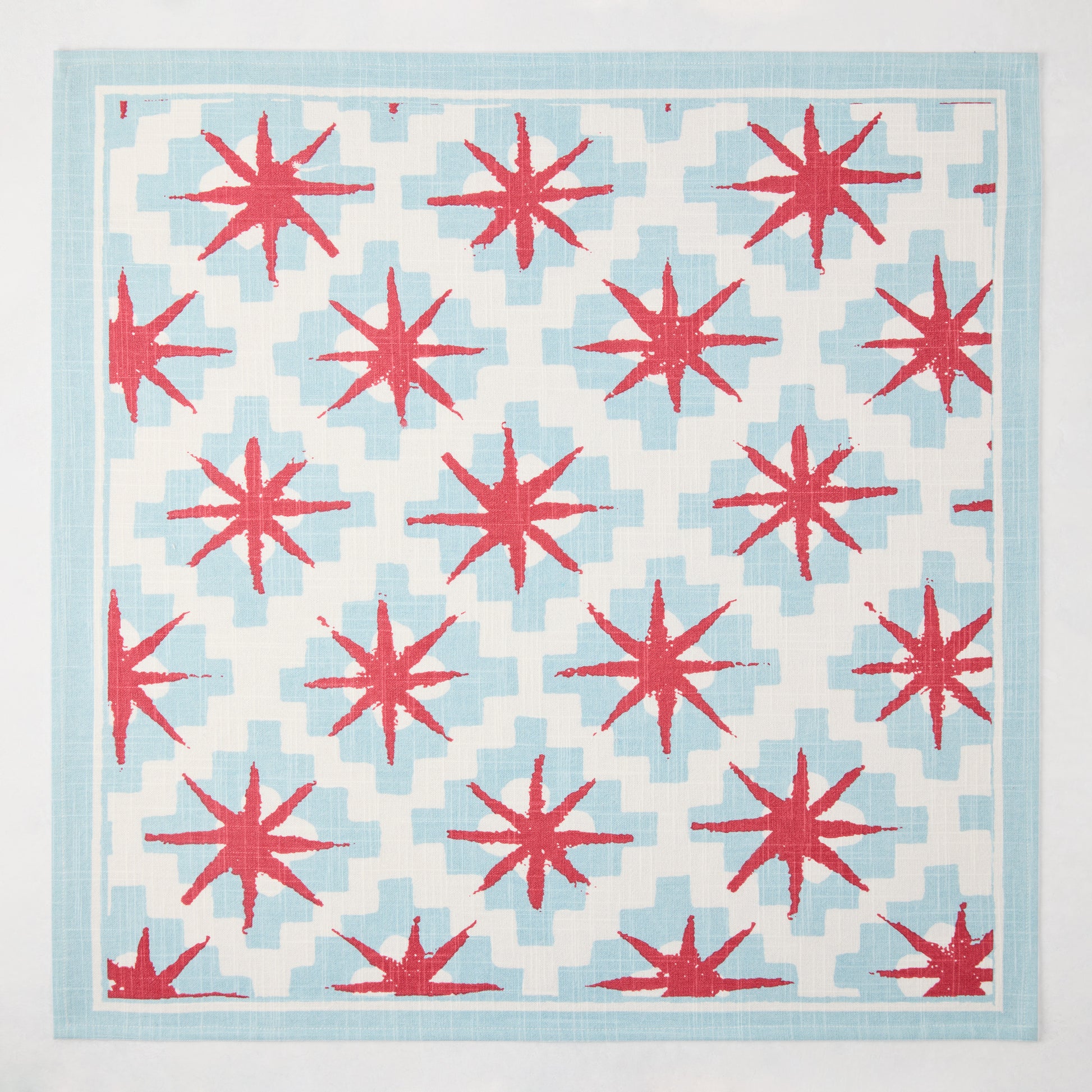 Peter Dunham + Hudson Grace Blue Starburst Printed Napkin, 100% cotton slub, red starbursts on blue geometric.