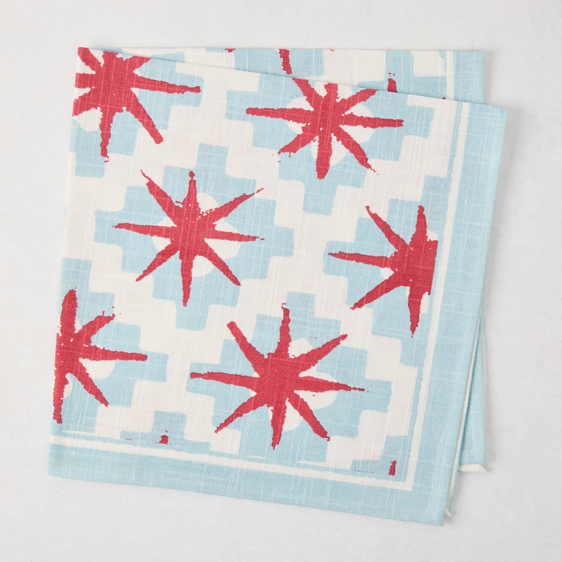 Peter Dunham + Hudson Grace Blue Starburst Printed Napkin, 100% cotton slub, red starbursts on blue geometric.