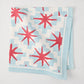 Peter Dunham + Hudson Grace Blue Starburst Printed Napkin, 100% cotton slub, red starbursts on blue geometric.