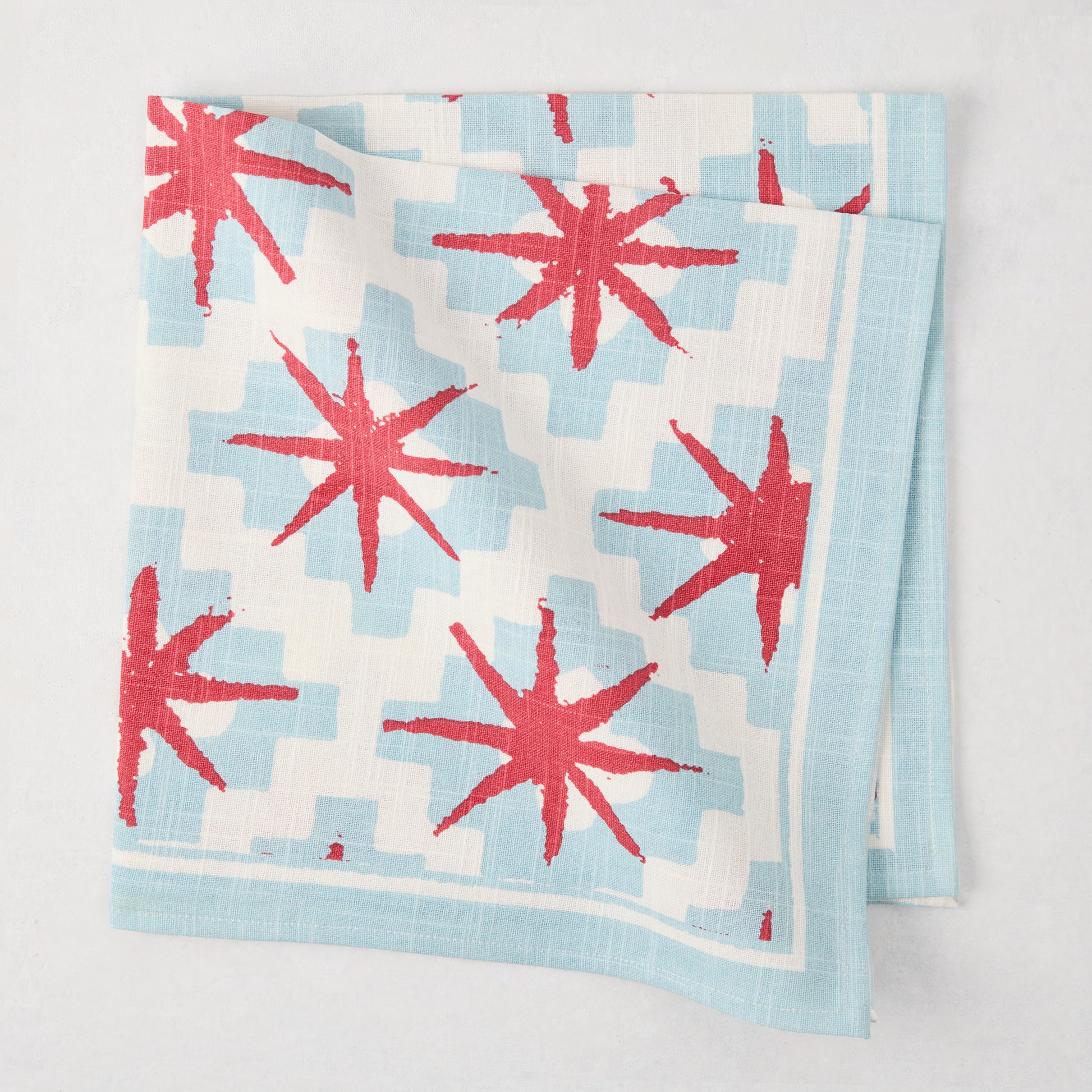 Peter Dunham + Hudson Grace Blue Starburst Printed Napkin, 100% cotton slub, red starbursts on blue geometric.
