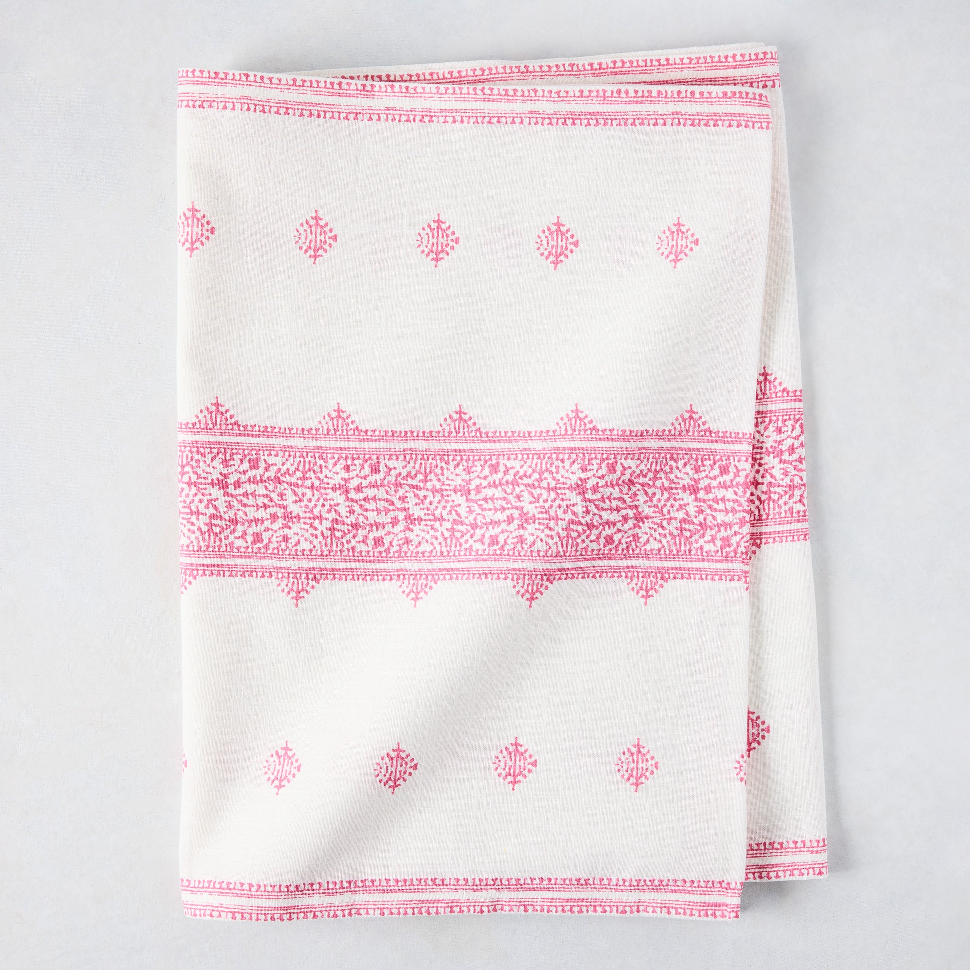 Bright pink Fez printed cotton slub table runner, folded, with intricate patterns on white.