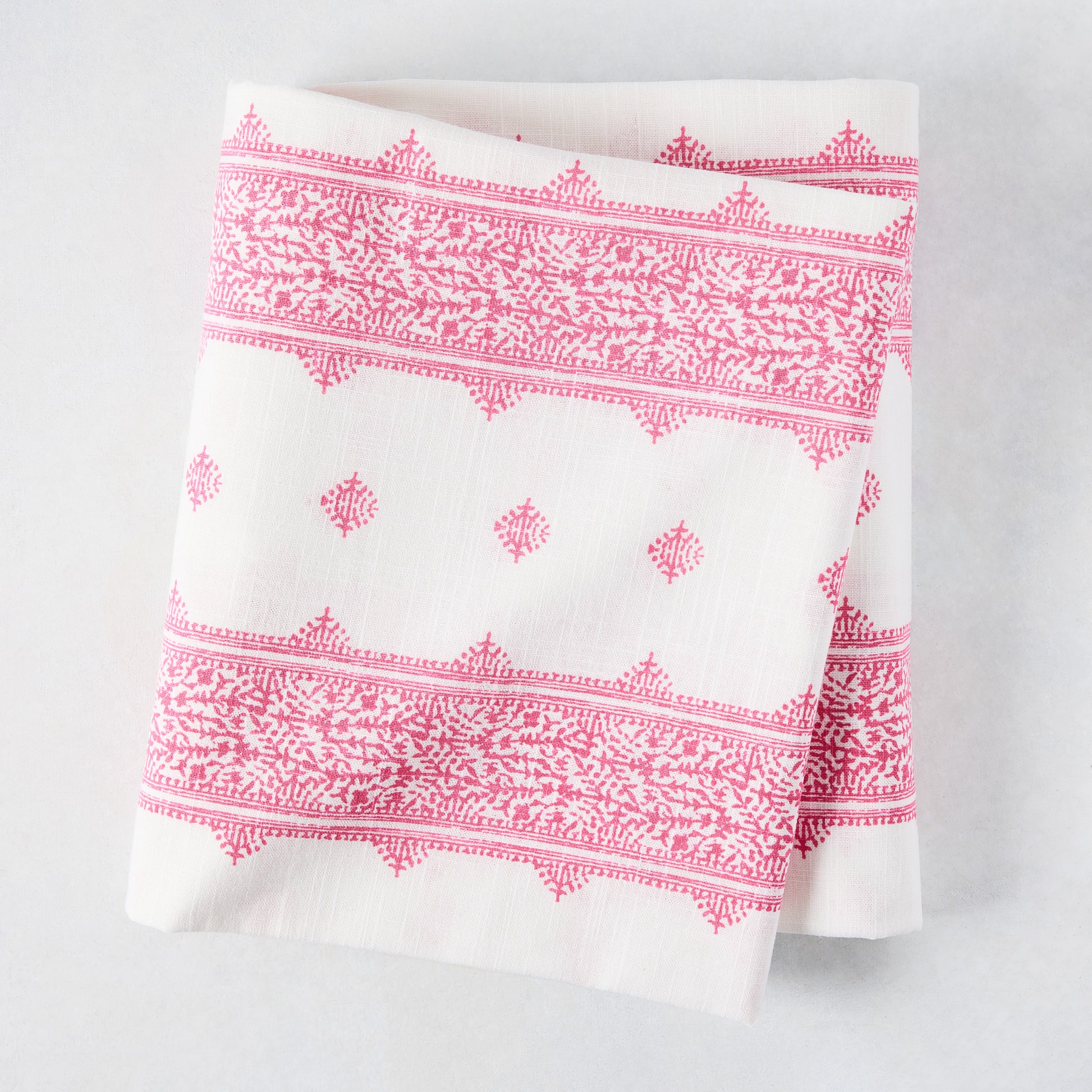 Folded Peter Dunham + Hudson Grace Bright Pink Fez Stripe cotton slub tablecloth with intricate pattern.