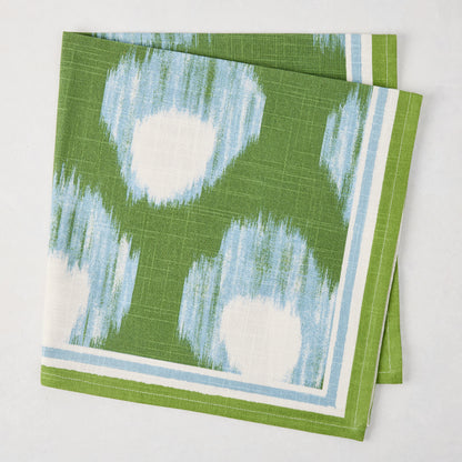 Green Bukhara Ikat Printed Napkin, 100% cotton slub, with blue and white blurred pattern and striped border.