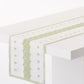 Peter Dunham + Hudson Grace green Fez stripe 108-inch cotton slub table runner on a white table.