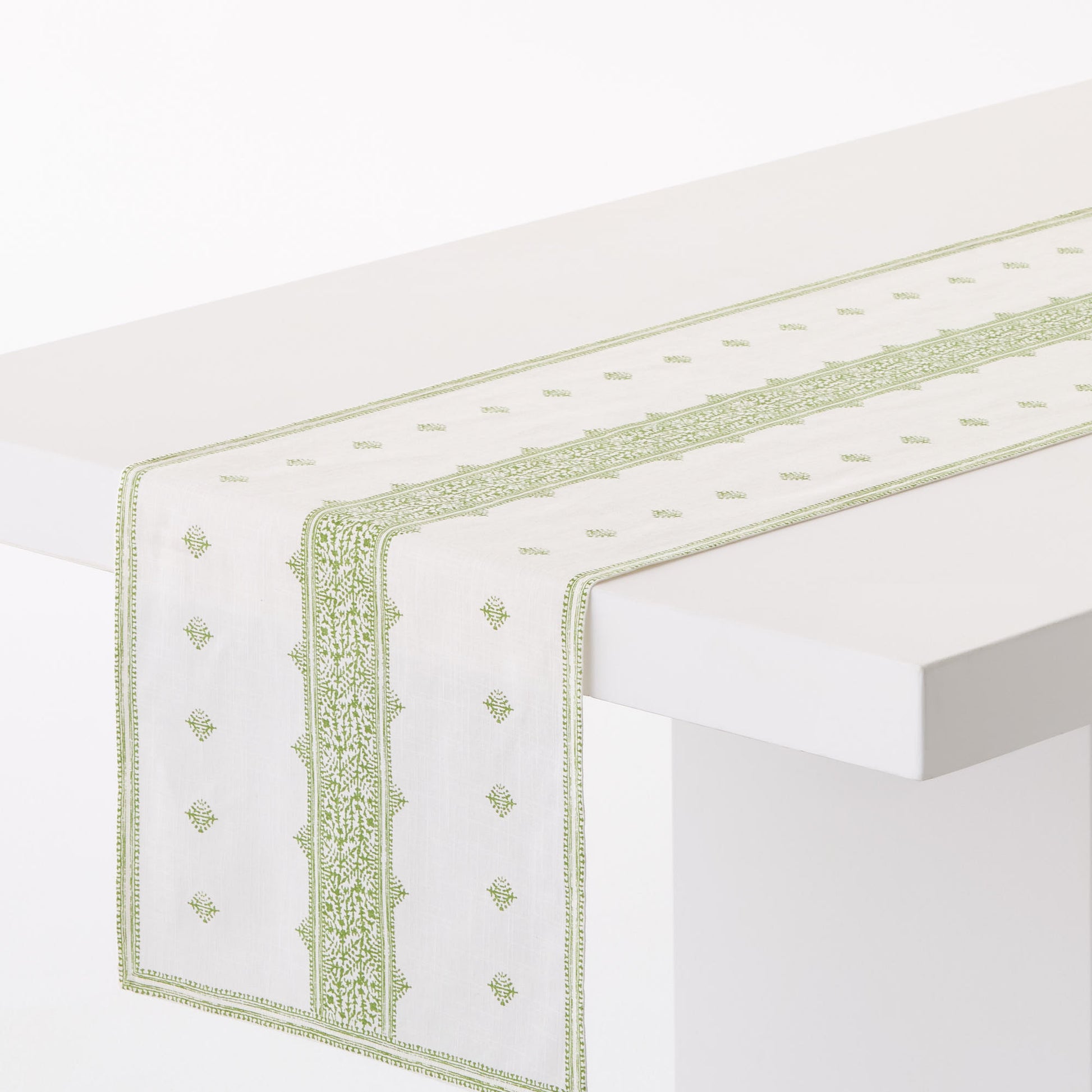Peter Dunham + Hudson Grace green Fez stripe 108-inch cotton slub table runner on a white table.