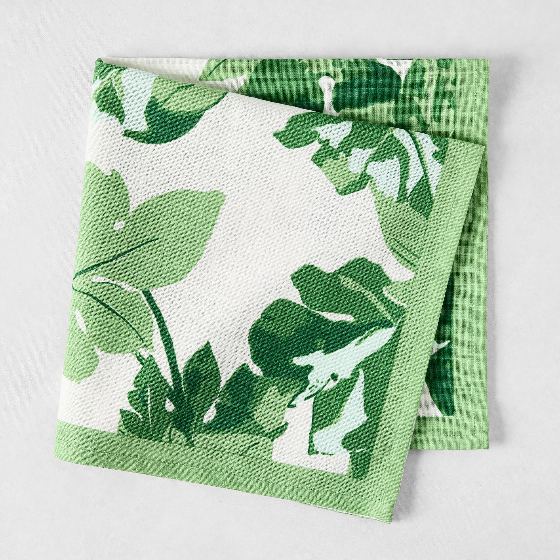 Peter Dunham + Hudson Grace Green Fig Leaf printed white cotton napkin with green border.