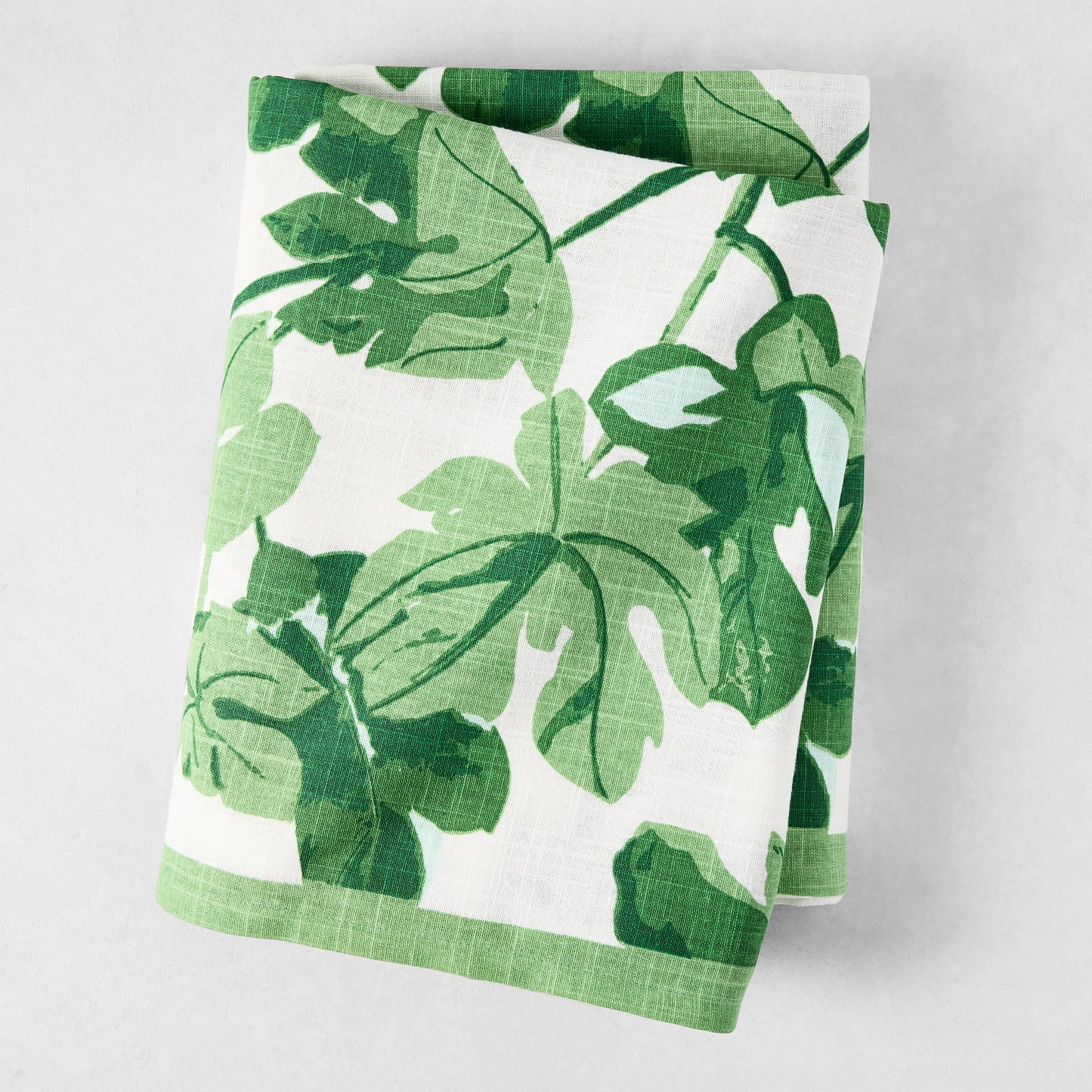 Peter Dunham + Hudson Grace Green Fig Leaf Printed White Tablecloth, 100% cotton slub, folded.