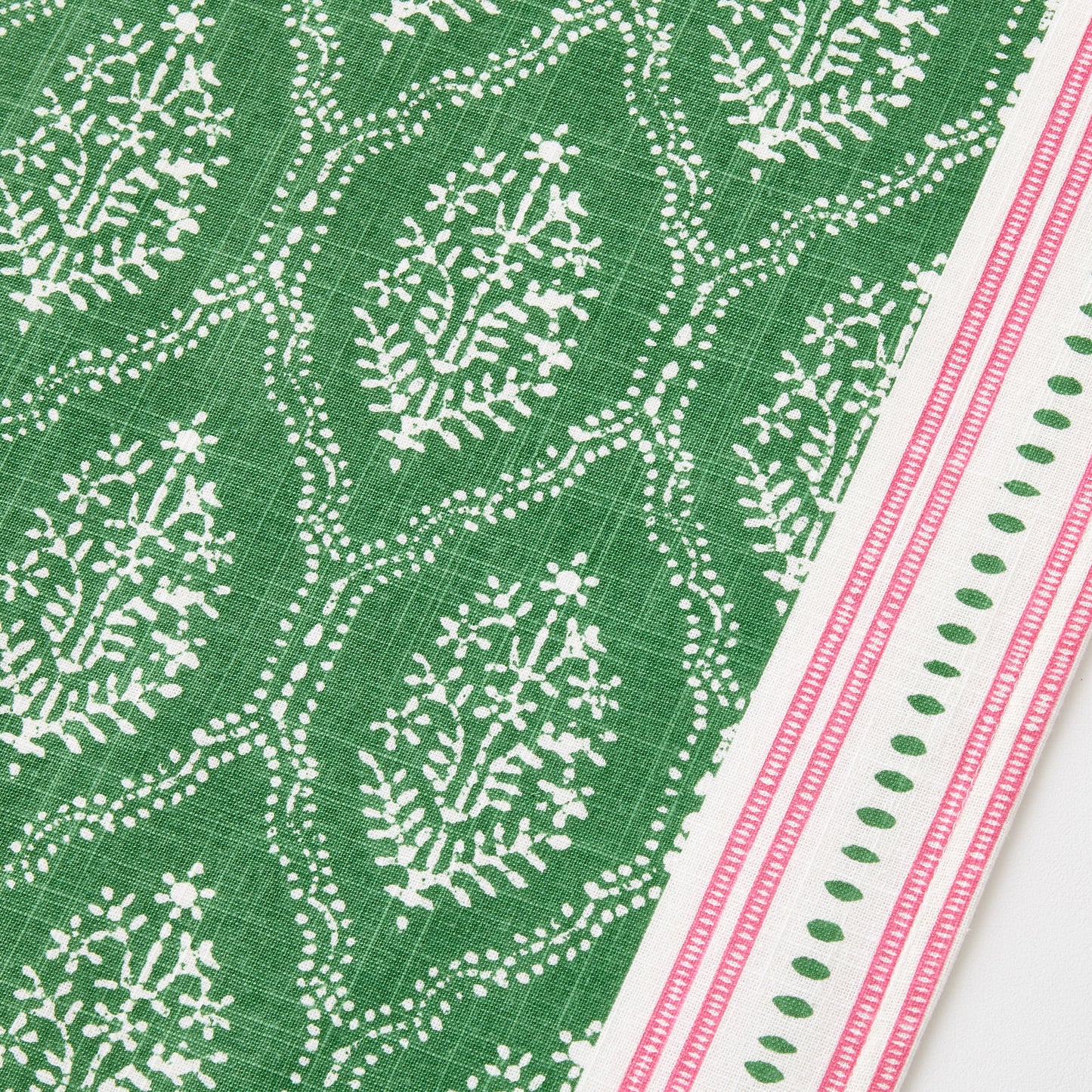 Green cotton slub table runner with white Jaali floral block print and pink striped border.