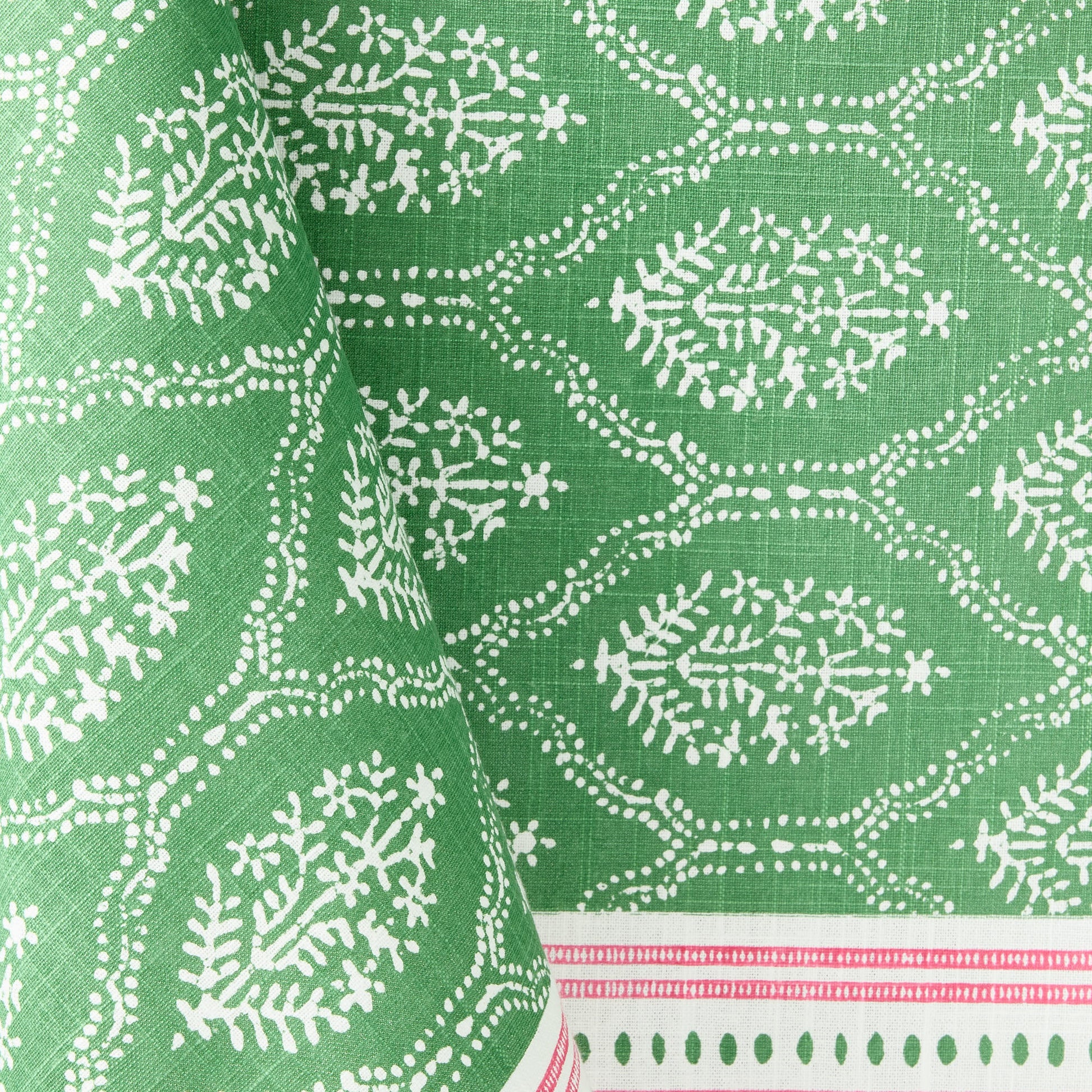Green cotton slub tablecloth with white Jaali floral block print and a decorative pink border.