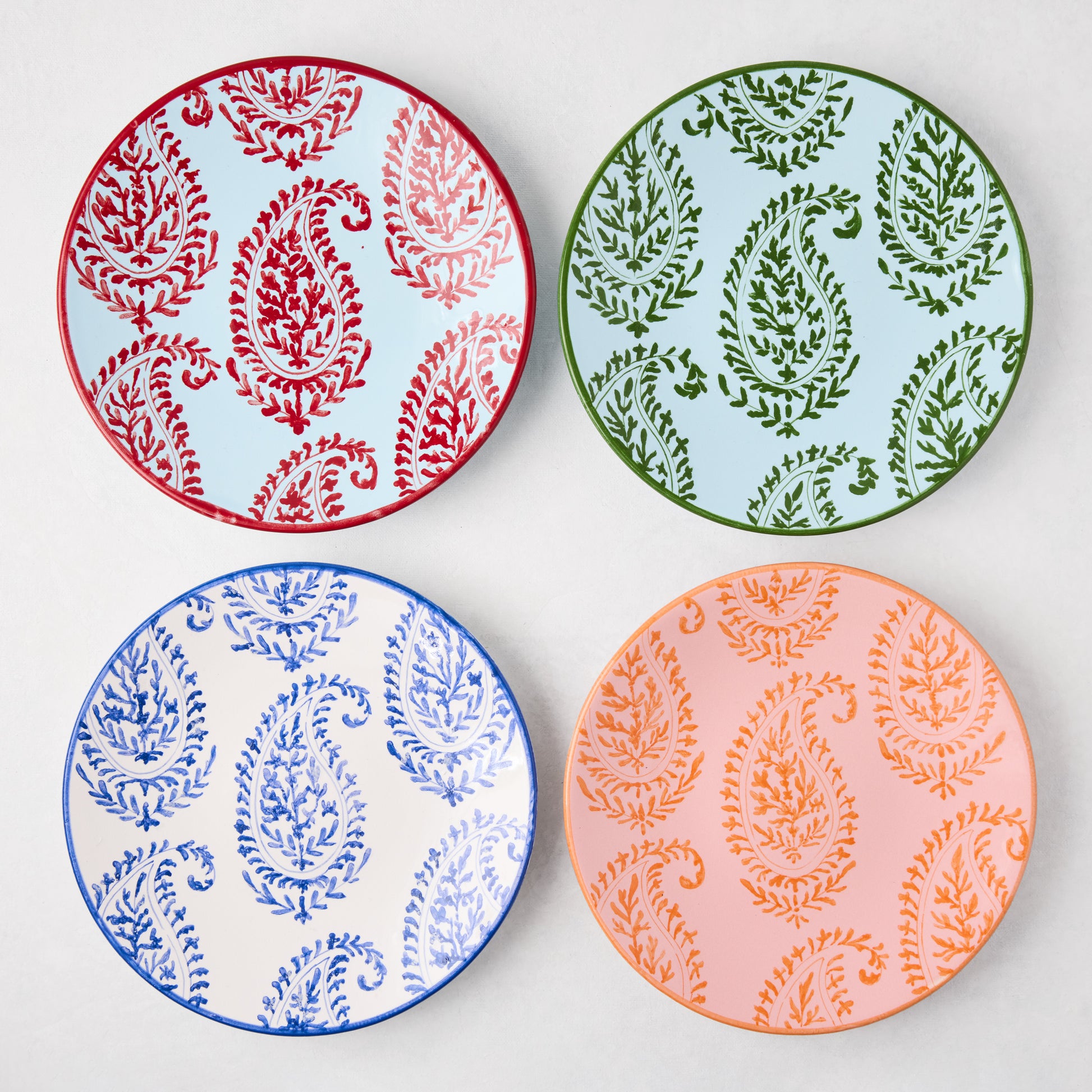 Four Peter Dunham + Hudson Grace hand-painted paisley salad plates in red, green, blue, and orange.